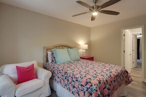 Une chambre à coucher comprenant un lit, une table de chevet, une chaise et un ventilateur de plafond.