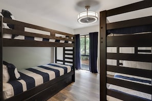 A bunk bed room with a ceiling fan, a window with curtains, and a wooden floor. - Spacious Villa Walk to Coligny Beach (Hilton Head Island)