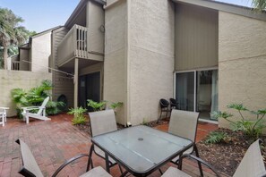 A patio area with a table and chairs, surrounded by plants and a small seating area.