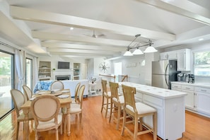 A spacious kitchen with white cabinetry, a central island, and a dining area with wooden chairs and a table. - 6 Bedrooms, Lakefront, Hot-Tub & Private Dock (Semora)