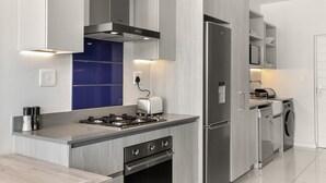 A modern kitchen with a built-in gas stove, stainless steel appliances, and a microwave. - Modern And Trendy 1 Bed Across From Rosebank Mall (Johannesburg)