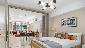 Ett modernt hotellrum med en stor säng, ett skrivbord och en sittgrupp med stolar.