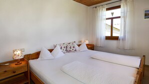 Un letto matrimoniale con biancheria bianca, una testata in legno e un comodino con una lampada.