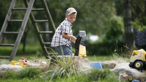 Un bambino gioca all'aperto con macchinari da costruzione giocattolo.