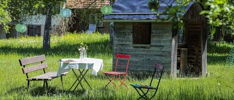 Une structure rustique en bois, avec une petite table et des chaises, située dans un espace verdoyant.