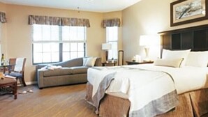 Une chambre d’hôtel avec un grand lit, un canapé, un fauteuil et un bureau avec une lampe.