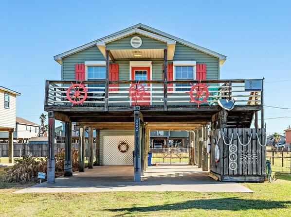 A two-story building with a balcony, a wooden deck, and a sign indicating it is a vacation rental.