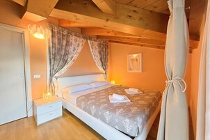 Un dormitorio con cama, mesita de noche, cortinas e imagen enmarcada en la pared.