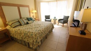 Una camera d'albergo con un letto grande, due poltrone, una scrivania e un televisore.