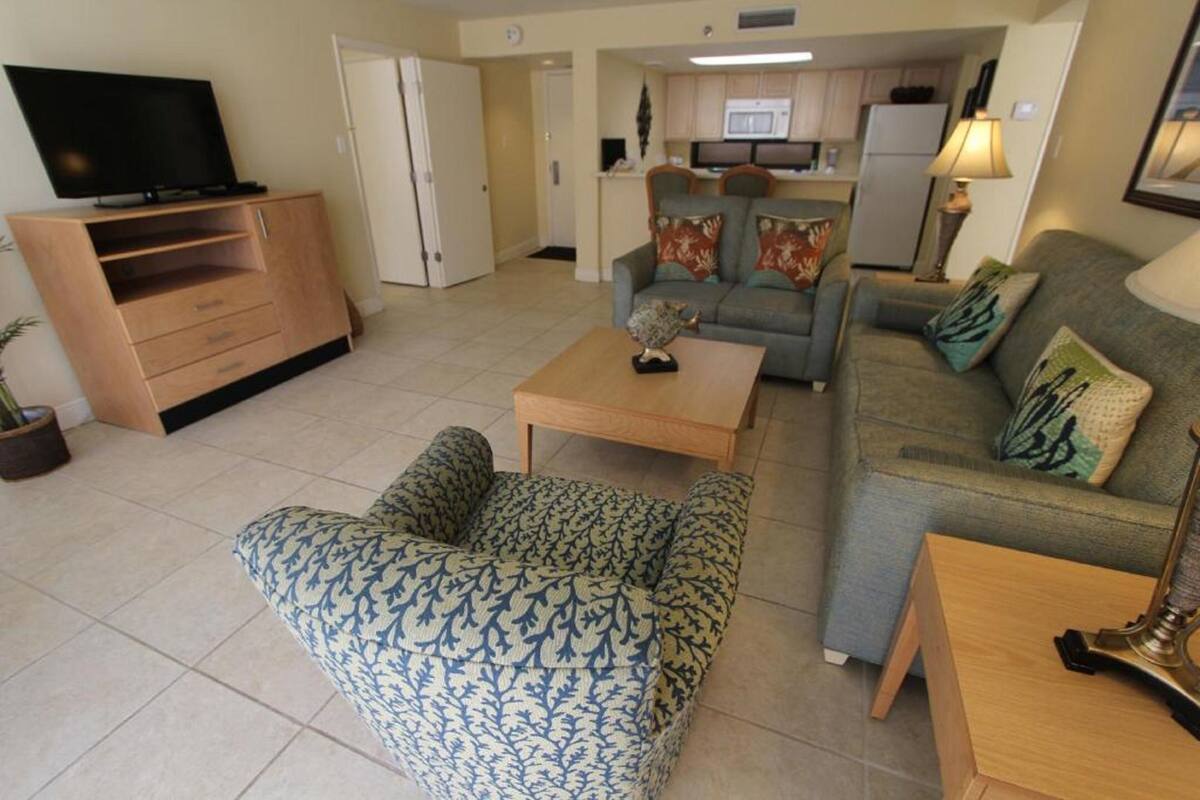 A living room with a sofa, a coffee table, and a TV on a wooden cabinet.