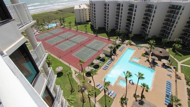 Un hotel con campo da tennis, piscina e vista sull'oceano.