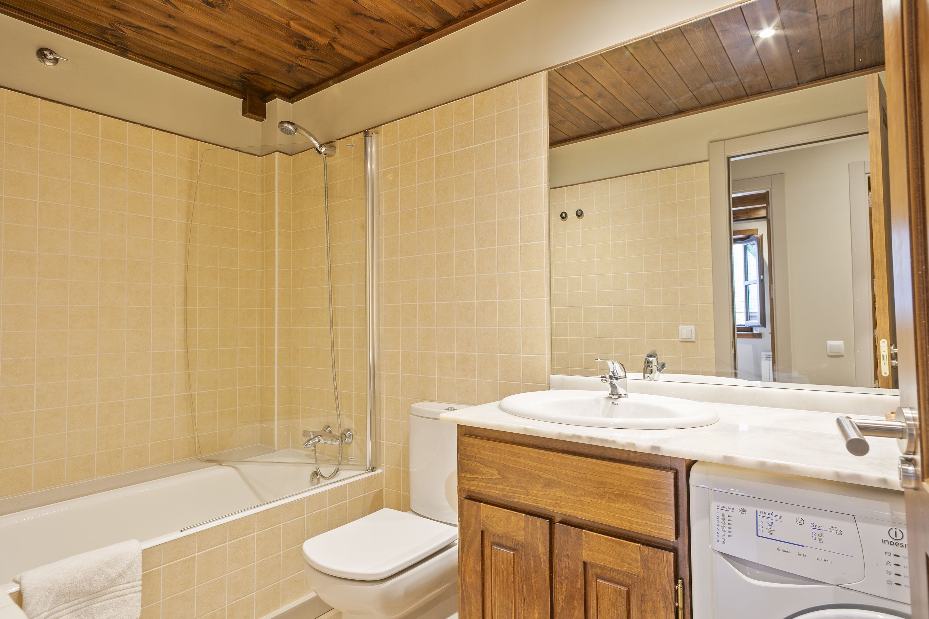 A bathroom with a bathtub, toilet, and a washing machine.