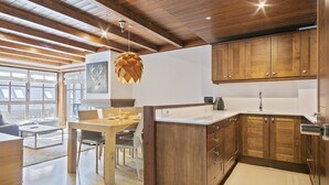 A modern kitchen with wooden cabinets, a white countertop, and a hanging light fixture. - Luderna - Apartamento Val de Ruda B14 Paulet (Baqueira)