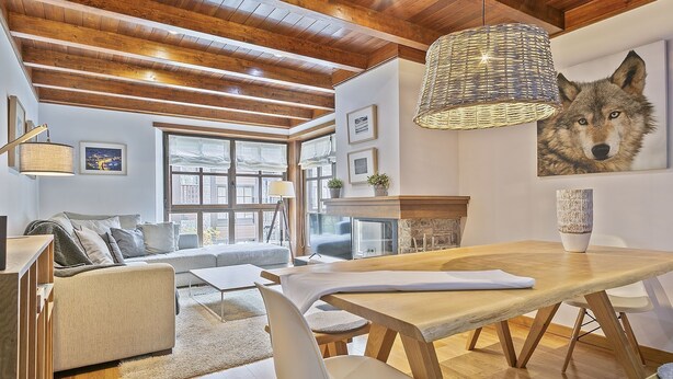 A modern living room with a wooden ceiling, a dining area with a wooden table, and a large painting of a wolf on the wall. - Luderna - Apartamento Val de Ruda B15 Baretja (Baqueira)