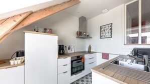 Une cuisine moderne avec des armoires blanches, un plan de travail en bois, un four encastré, un évier et une fenêtre donnant sur un beau paysage.
