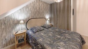 Une chambre à coucher avec un lit, deux tables de chevet, une lampe, un luminaire au plafond et un mur décoré de motifs.