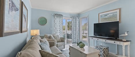 A living room with a sofa, TV, and a window with curtains.