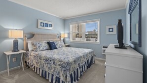 A bedroom with a bed, two bedside tables, a dresser, and a window with blinds.