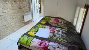 Een slaapkamer met een bed, een stenen muur, een deur en een dakraam.
