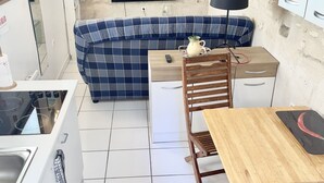 Een gezellige, compacte ruimte met een kitchenette, een bank, een eettafel en een aan de muur bevestigde televisie.