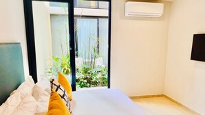 A hotel room with a bed, a view of greenery outside, and an air conditioning unit on the wall. - 1 Bedroom apartment with views to green area and hamacs, Gym, Rooftop Pool (Playa del Carmen)