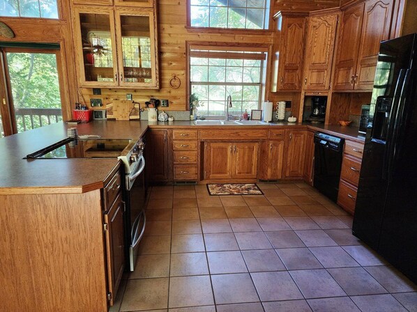 Enjoy cooking in this well-equipped kitchen with a large island, double sink, stove, and refrigerator.