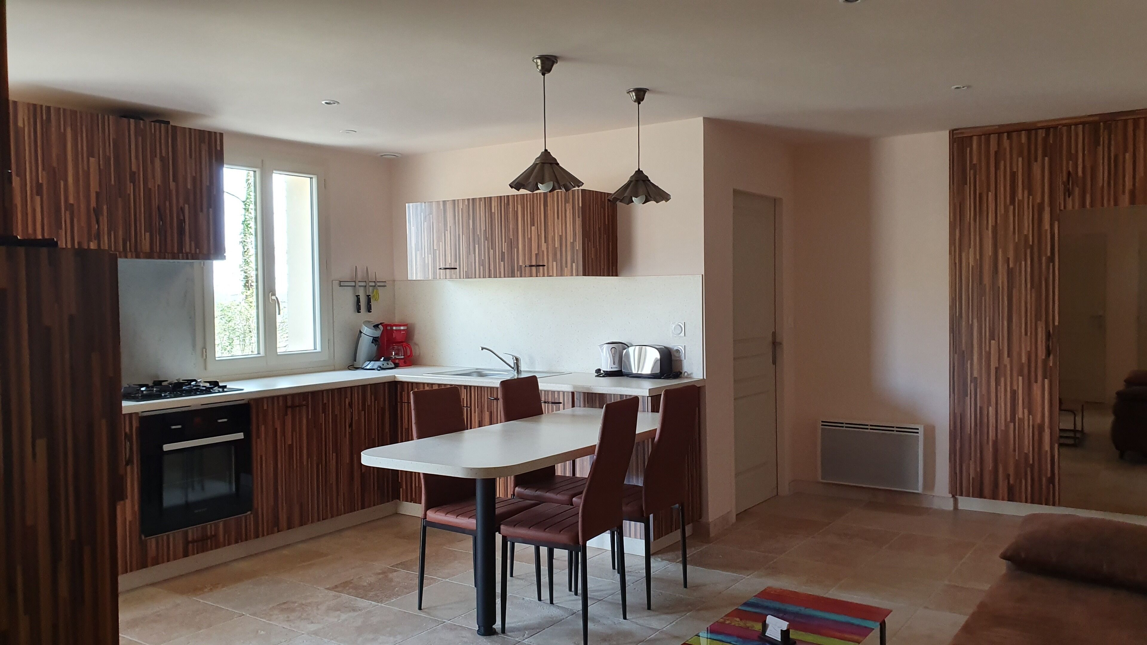 Una cocina moderna con armarios de madera, una mesa de comedor con sillas, una cafetera y un tostador.