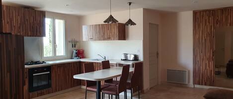 Una cocina moderna con armarios de madera, una mesa de comedor con sillas, una cafetera y un tostador.