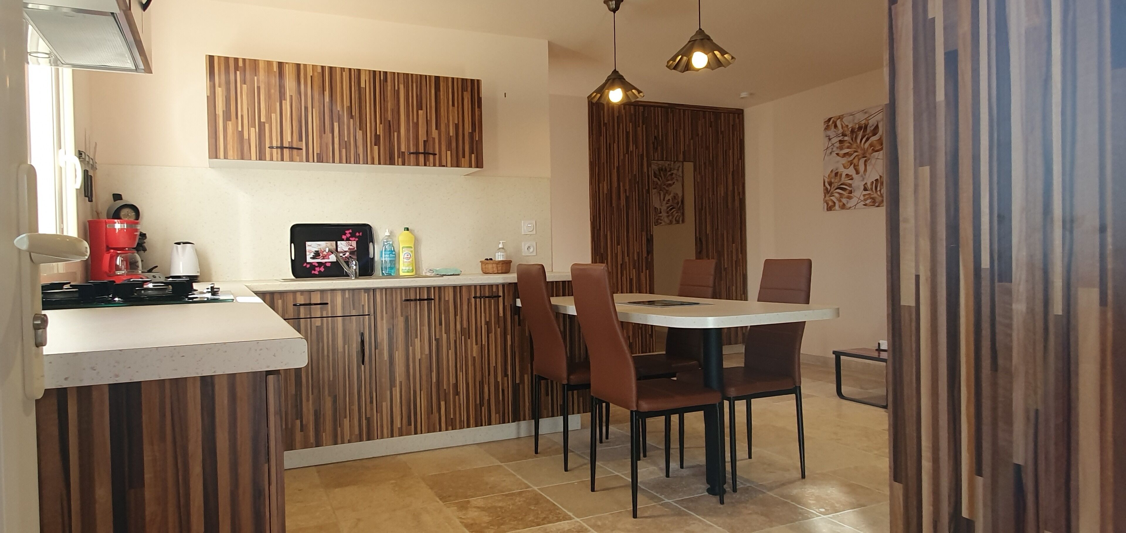 A modern kitchen with wooden cabinets, a dining table with chairs, and a coffee machine.