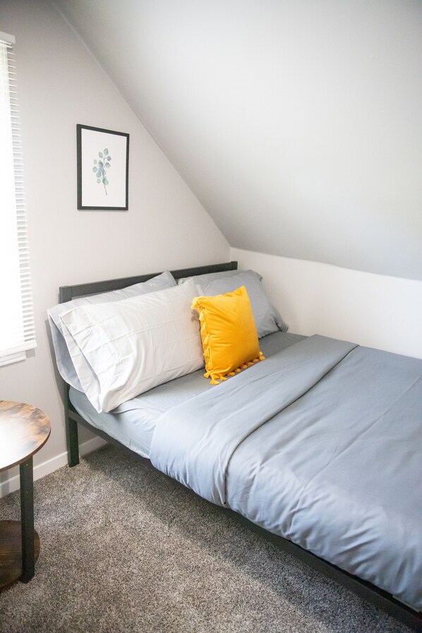 A bedroom with a bed, a framed picture on the wall, and a small round table. - Cute Home, Newly Remodeled, Great Location! (Grand Rapids)
