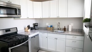 A modern kitchen with white cabinets, stainless steel appliances, and a granite countertop. - Cute Home, Newly Remodeled, Great Location! (Grand Rapids)