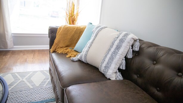 A brown leather sofa with a patterned rug and a window with curtains. - Cute Home, Newly Remodeled, Great Location! (Grand Rapids)