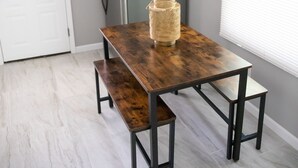 A dining area with a wooden table and benches, a chandelier, a refrigerator, and a window with blinds. - Cute Home, Newly Remodeled, Great Location! (Grand Rapids)