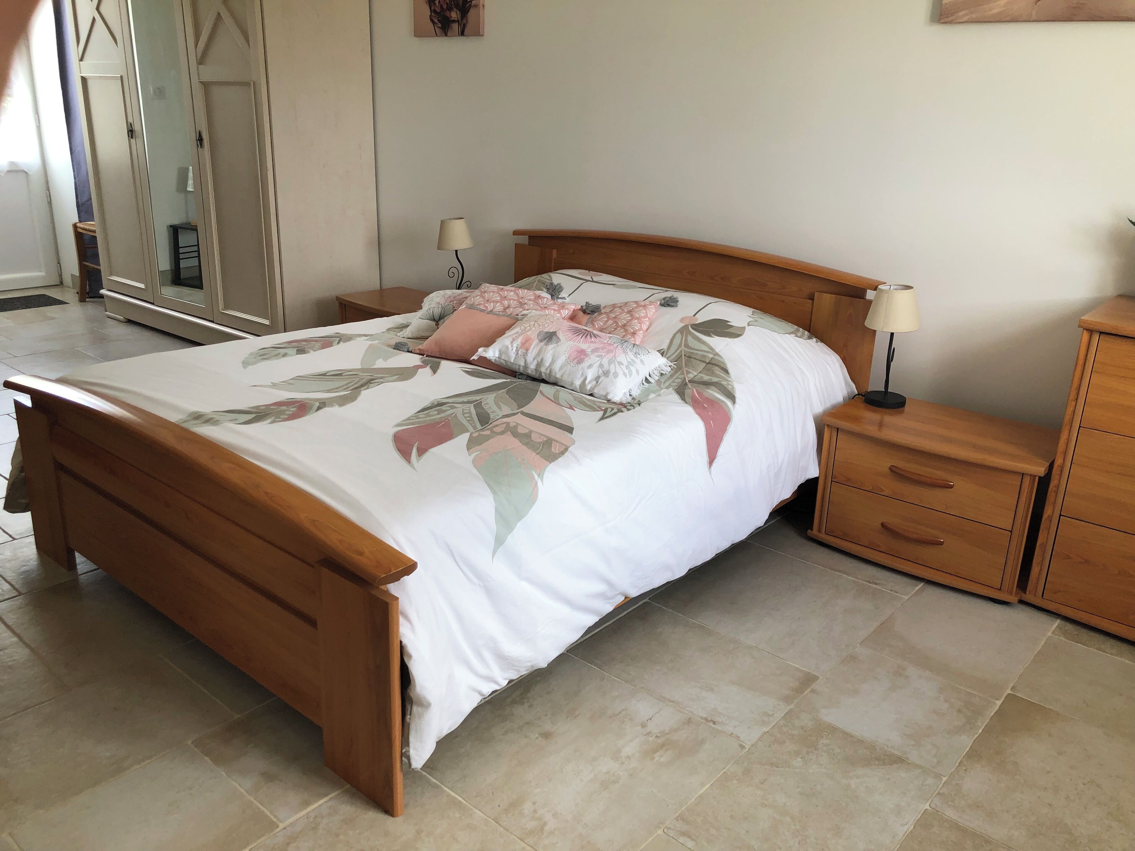 Een slaapkamer met een houten bed, een nachtkastje met een lamp en een kast.