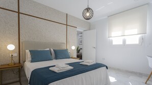 Un dormitorio moderno con una cama grande, mesitas de noche y una lámpara en el techo.