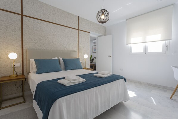 Un dormitorio moderno con una cama grande, mesitas de noche y una lámpara en el techo.