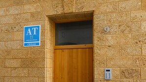 Edificio de piedra con puerta de madera y un letrero azul que indica una instalación de ATC.