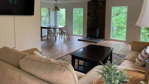 Un salon spacieux doté d’une cheminée, d’un ventilateur de plafond et d’un téléviseur fixé au mur.