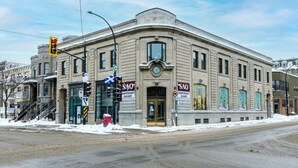 A historic building with a classic architectural style, featuring a prominent entrance with a clock and a sign indicating it is open. - Amazing and Perfectly Located Flat by Denstays (Montréal)