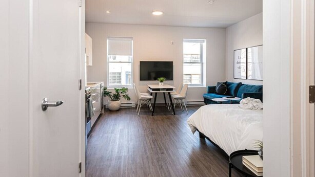 A modern bedroom with a bed, a TV, a desk, and a sofa. - Amazing and Perfectly Located Flat by Denstays (Montréal)