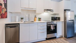 Een moderne keuken met witte kastjes, roestvrijstalen apparatuur en een vaatwasser.