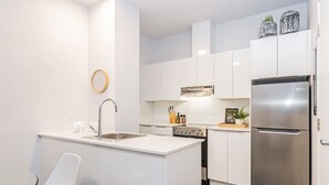 Una cocina moderna con armarios blancos, un refrigerador de acero inoxidable y una pequeña isla con fregadero.