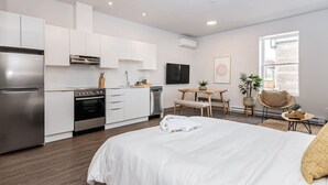 A modern kitchen with white cabinets, stainless steel appliances, and a dining area with a table and chairs. - Brand New and Perfectly Located Flat in Le Plateau by Denstays (Montréal)