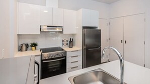 Una cocina moderna con armarios blancos, electrodomésticos de acero inoxidable y un horno empotrado.