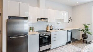 A modern kitchen with white cabinets, stainless steel appliances, and a central island. - St-Denis 209 · Amazing New Apartment Close to Mount Royal (Le Plateau) by Denstays (Montréal)