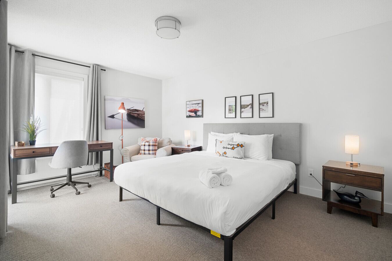 Una camera d'albergo con un letto grande, una scrivania, una sedia, un comodino con una lampada e una TV a parete.