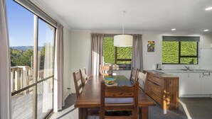 A modern kitchen with white cabinets and a large window. - Kapiti Views - Waikanae Beach Holiday Home (Waikanae Beach)