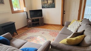 Een woonkamer met een grote bank, een salontafel, een televisie en een schilderij aan de muur.