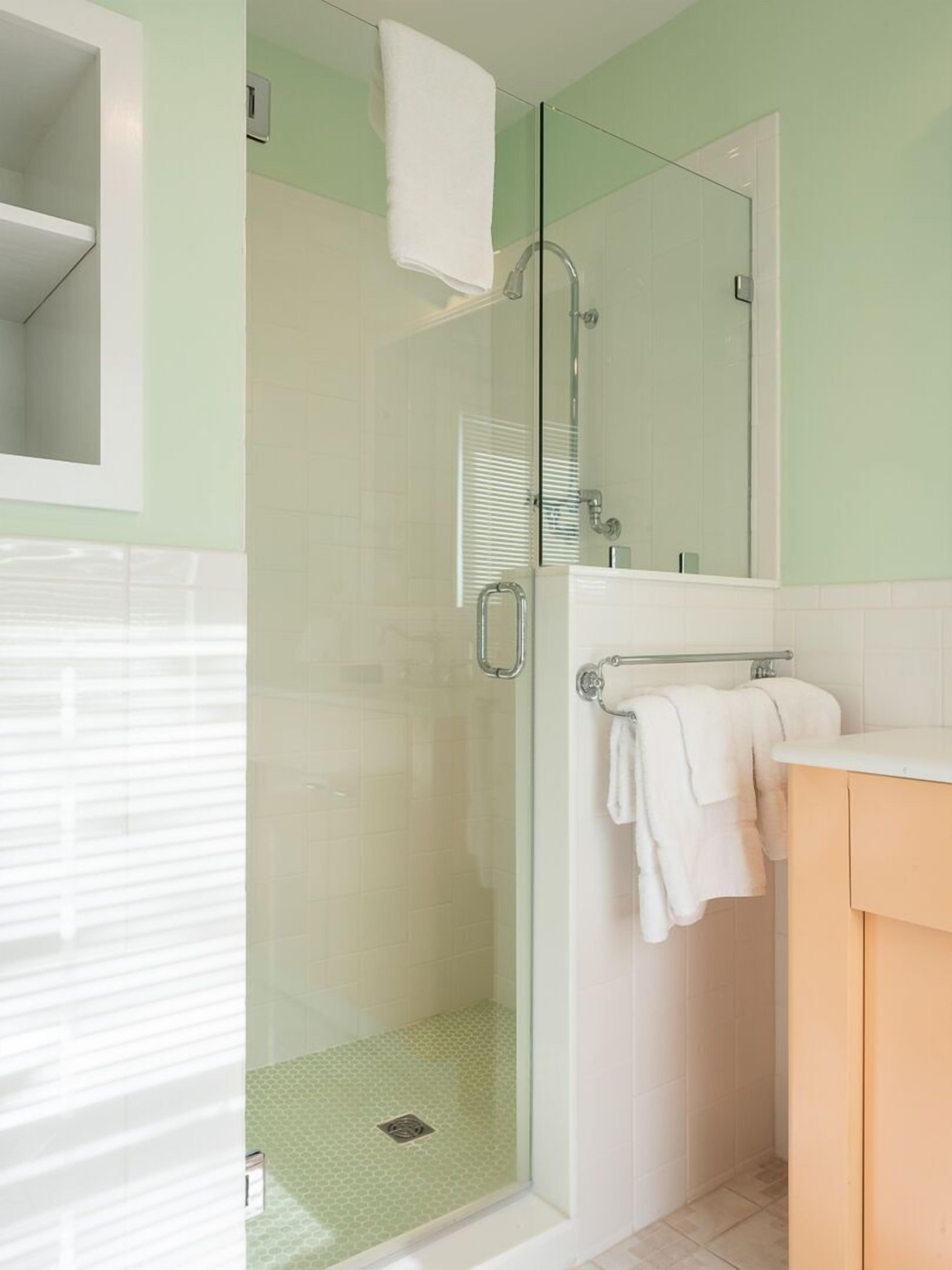 Un bany modern amb una cabina de dutxa de vidre, un lavabo blanc i un mirall damunt del lavabo.