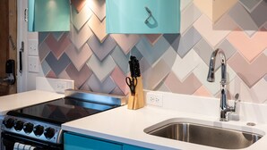 A kitchen with a gas stove, a stainless steel sink, and teal cabinets. - Retro Apartment | Furnished Monthly Rental in Belmont (Charlottesville)